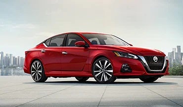 2023 Nissan Altima in red with city in background illustrating last year's 2022 model in Sutherlin Nissan Vero Beach in Vero Beach FL